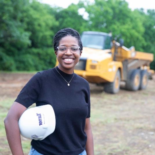 Michaela 柯克 standing in front of a construction vehicle